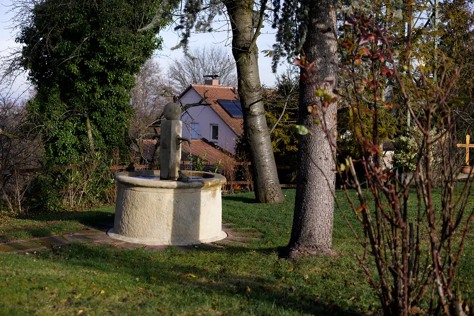 Runder Steinbrunnen im Garten des Weinberghauses zwischen alten Bäumen