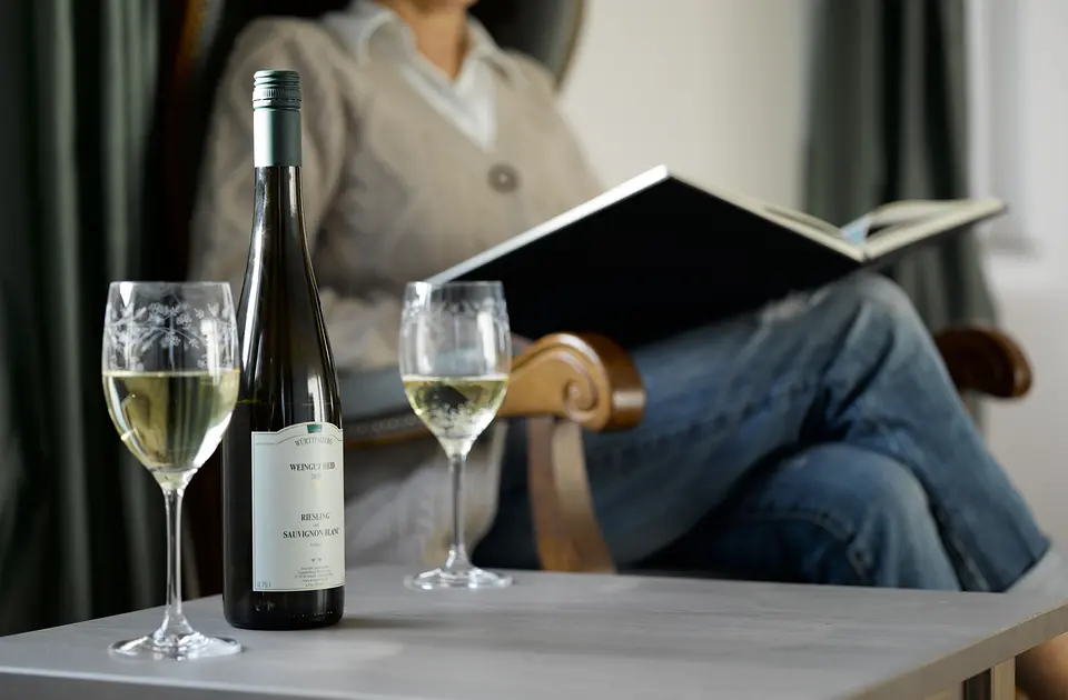 Flasche Fellbacher Riesling und zwei Gläser Weißwein auf dem Tisch, dahinter ein lesender Gast