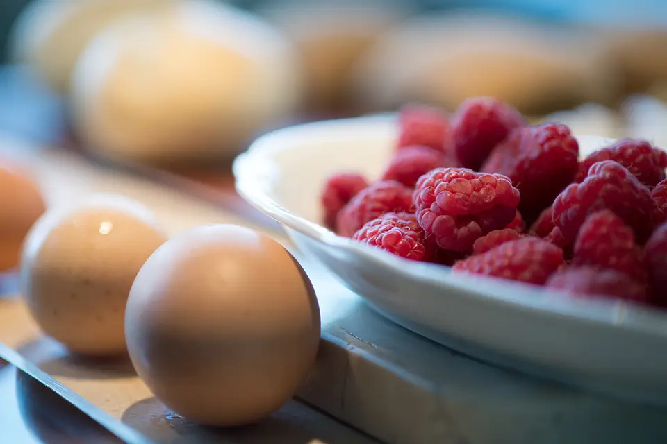 Frische Eier und eine Schale Himbeeren auf dem Frühstückstisch