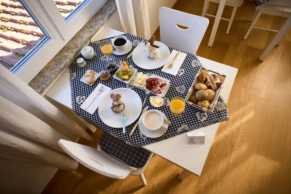 Frühstück für zwei von oben: Eier unter Filzwärmern, Käse, Schinken, Obst, Brötchen, Orangensaft und Kaffee