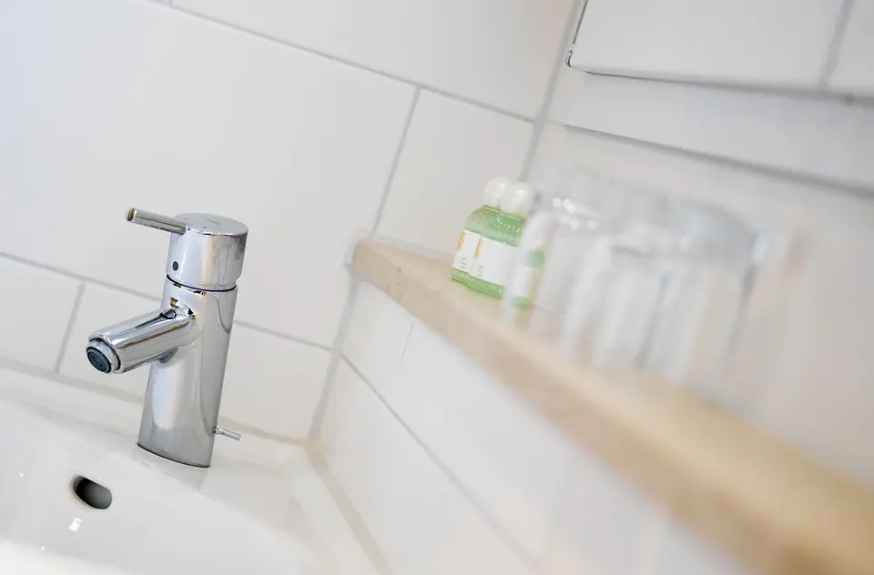 Waschbecken mit Armatur und Pflegeprodukten im Badezimmer des Grünen Zimmers