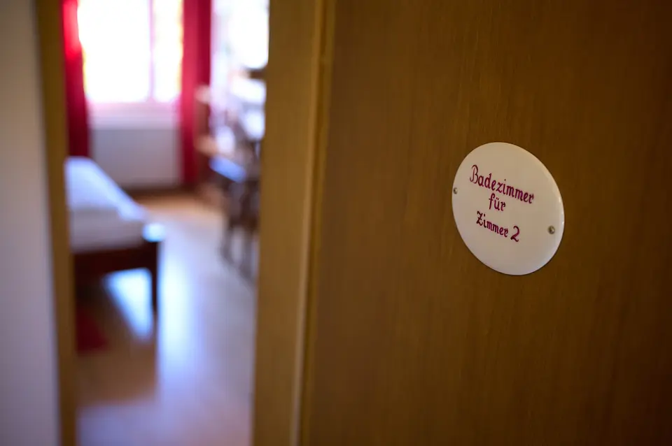 Emailschild „Badezimmer für Zimmer 2“ an der Tür – das Bad des Bauernzimmers liegt zwei Schritte über den Gang