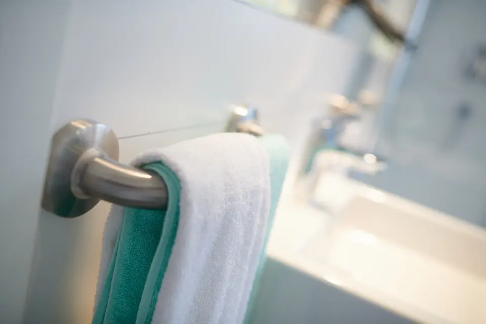 Frische Handtücher in Weiß und Türkis an der Stange im Badezimmer